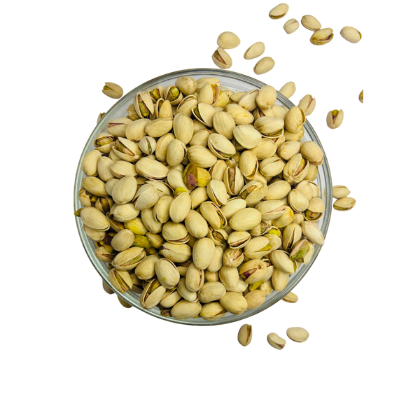 Nuts for Wellness Pistachios in a glass bowl with some scattered on a white background