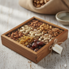 Wooden box with assorted nuts and dried fruits on a rustic surface