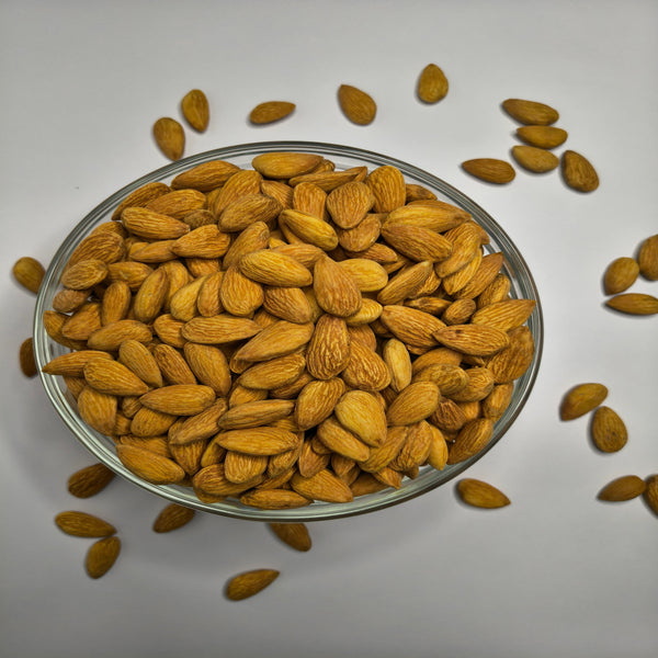 Glass bowl filled with almonds on a white background