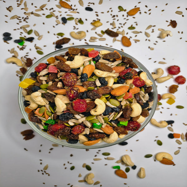 Assorted trail mix in a glass bowl on a light background