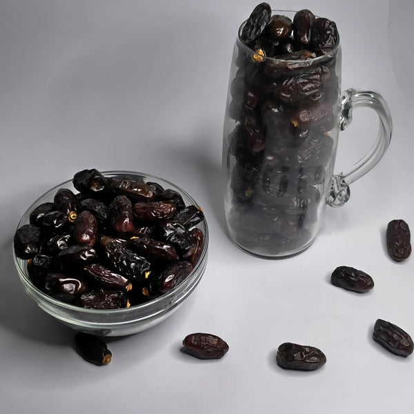 Date fruits in a glass bowl and mug on a white background