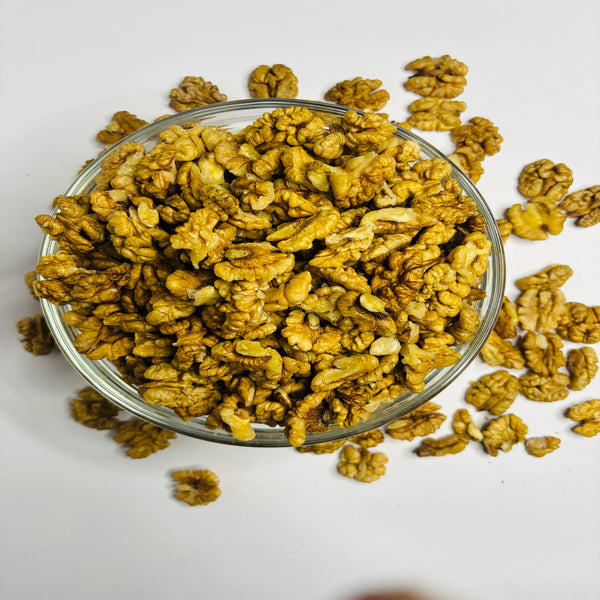 Glass bowl filled with roasted walnuts on a white background