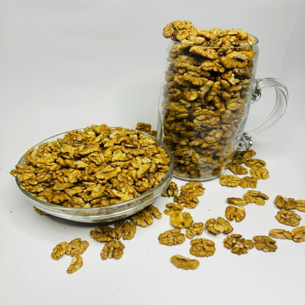 Glass bowl and mug filled with walnuts on a white background