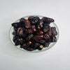 Glass bowl filled with dark brown dates on a light gray background