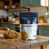 Nuts For Wellness Bag of premium golden raisins on a kitchen counter with a bowl of raisins.