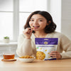 Nuts For Wellness Woman enjoying a snack with a bag of Golden Raisins on a table with a cup of tea and bowl of snacks.