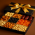 Gift box with a gold bow containing assorted dried fruits and nuts on a brown background
