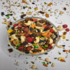 Assorted trail mix in a glass bowl on a light background