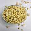 Glass bowl filled with pistachios on a light gray background