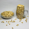 Glass bowl and mug filled with pistachios on a white background