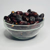Glass bowl filled with dark dried fruits on a white background